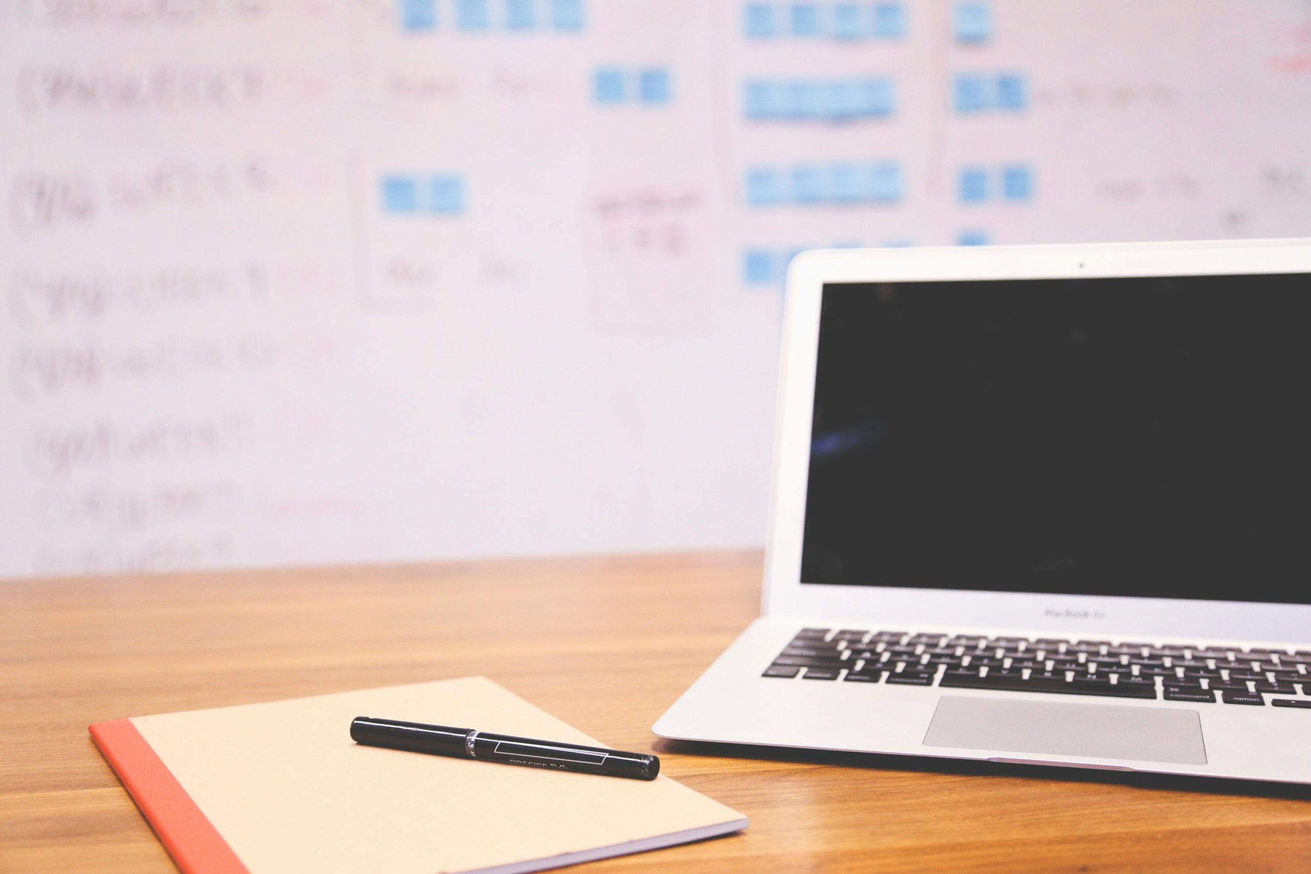 Clean and organized workspace with a laptop, notepad, and pen for planning and projects.
